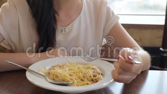 在咖啡馆里吃意大利面和培根的年轻女人视频的预览图