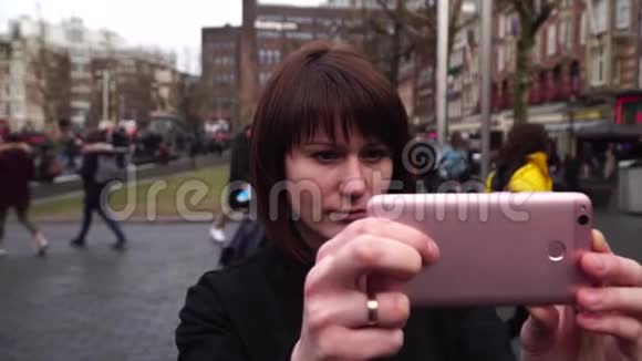 女游客在城市的智能手机上拍照阿姆斯特丹伦勃朗慢动作视频的预览图