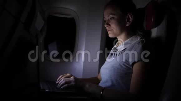 年轻女子晚上在飞机上做笔记本视频的预览图