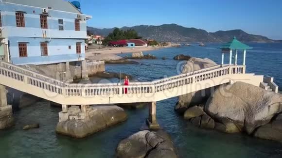 女孩站在房子和海岩之间的桥上视频的预览图
