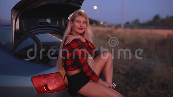 性感女人坐在车上用耳机听音乐视频的预览图