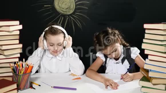 学校观念孩子们坐在一张桌子旁桌子后面放着一堆书和一块黑板上面有图纸孩子们玩得开心视频的预览图