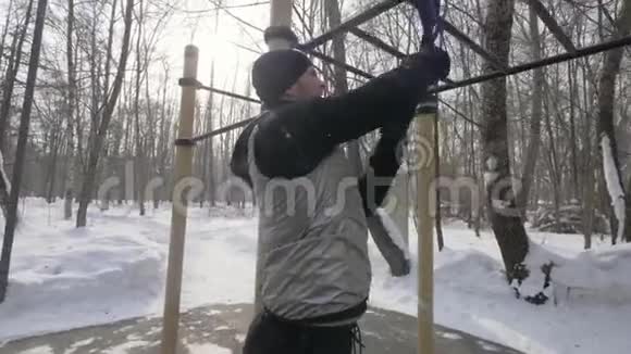 在冬季公园的运动场上健身男子使用膨胀机进行户外训练视频的预览图
