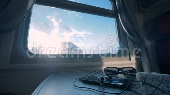 在火车车厢的桌子上用耳机和眼镜合上智能手机视频的预览图