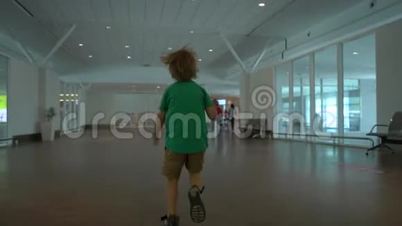 一个小男孩手里拿着白色玩具飞机在机场里奔跑的慢镜头自由概念视频的预览图