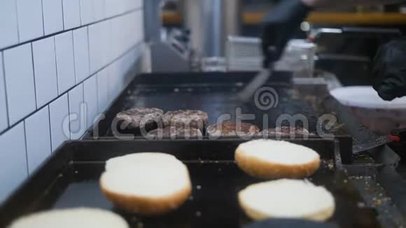 厨师油炸汉堡馅饼和清洁烧烤炉在餐厅厨房4K视频的预览图