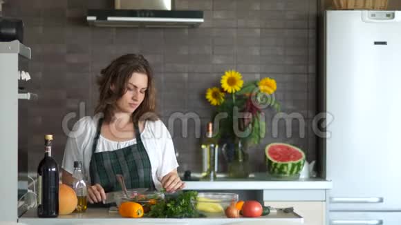 一个漂亮的卷曲的黑发女人拿着刀和一个开槽的勺子在厨房里跳舞现代厨房内部视频的预览图