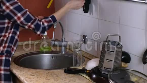 厨房里穿格子衬衫的女人戴着橡胶手套在水槽里洗玻璃视频的预览图