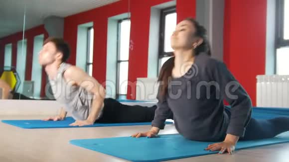 灵活的男人和女人在健身课的地毯上做运动视频的预览图