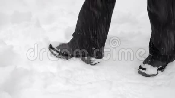 穿着黑色裤子和靴子的腿艰难地穿过雪堆视频的预览图