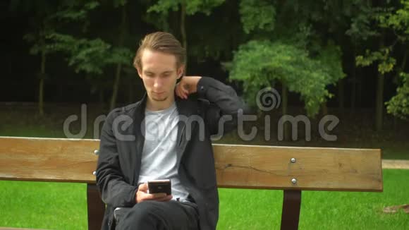 年轻人用智能手机建立社交网络在公园里休息视频的预览图