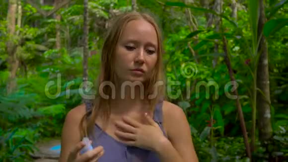 热带森林中的年轻女子在皮肤上喷洒蚊子视频的预览图