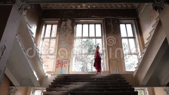 一个穿着长裙的女人正在一所废弃的房子里走楼梯视频的预览图