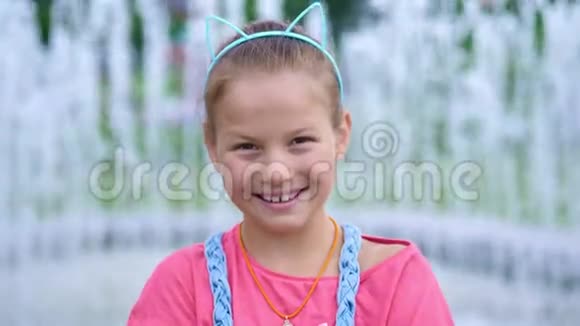 一个微笑快乐的八岁女孩的肖像在一个有趣的箍她的头上有耳朵头发装饰背景资料视频的预览图