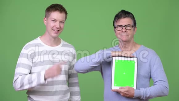 高级帅哥和年轻帅哥一起展示数码平板电脑视频的预览图