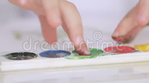 一个小孩子用水彩画用颜料把手指弄湿视频的预览图