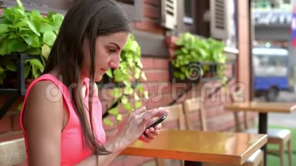 女人在电话里说话在街上的咖啡馆里发信息4k视频的预览图