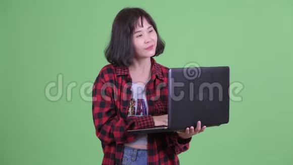 快乐的亚洲时髦女人用手提电脑思考视频的预览图