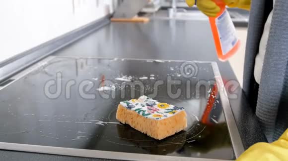 在厨房清理电炉时用洗涤剂喷上黄手套的年轻家庭主妇特写4k镜头视频的预览图