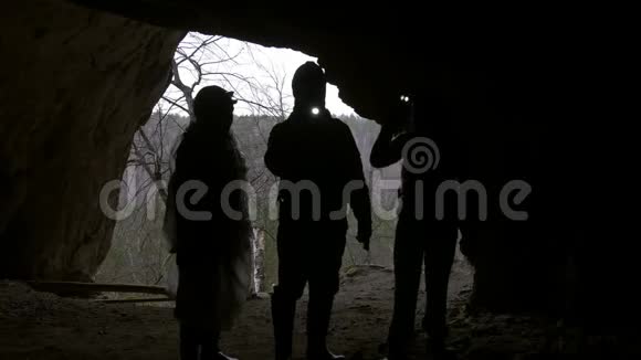 戴着头盔的徒步旅行者用手电筒进入黑暗的洞穴视频的预览图