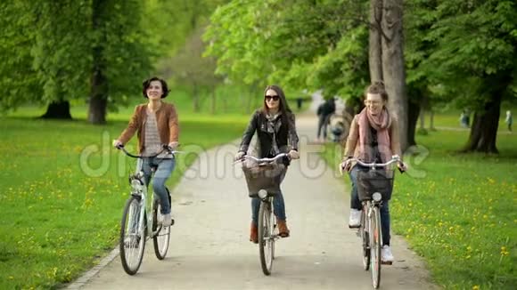 有趣的城市自行车在公园的三个可爱的女性朋友与惊人的微笑第一个女人有短卷发视频的预览图