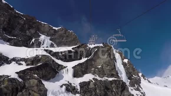 在冬季的滑雪场里带着岩石的椅子电梯上升到山顶视频的预览图