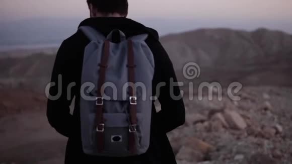 带背包的人独自在黄昏的沙漠中行走慢动作令人惊叹的日落山景寻找灵感视频的预览图
