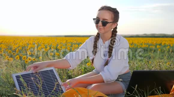 新技术女孩在向日葵上使用太阳能电池为笔记本电脑充电年轻女性使用太阳能视频的预览图