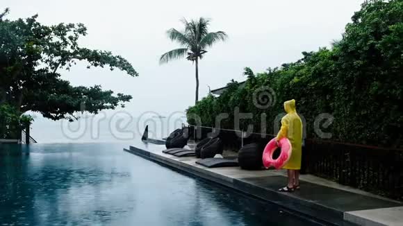 无论天气如何穿着黄色雨衣和甜甜圈的单身男子双臂抱着她享受假期男性游客视频的预览图
