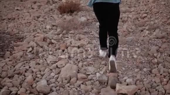 女孩在大沙漠石头上徒步旅行慢动作女旅行者带着大石头上山困难以色列视频的预览图