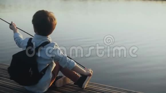 可爱的欧洲男孩在湖边码头玩棍子带背包的小孩子享受假期快乐的童年4K视频的预览图