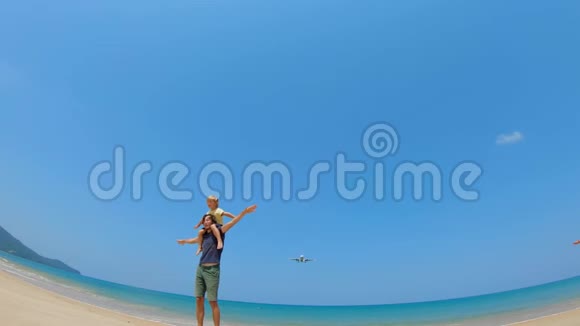 一对年轻父子的慢镜头一架飞机飞过他们麦考海滩普吉岛视频的预览图