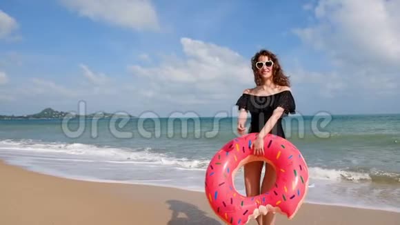 快乐的年轻女人带着太阳镜和游泳玩具欢迎你在海滩上玩水玩的女人玩得开心视频的预览图