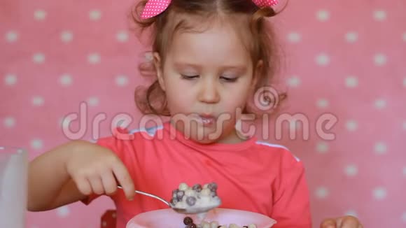 可爱的孩子吃谷物小女孩吃早餐麦片喝牛奶喝酸奶早上笑得开心视频的预览图