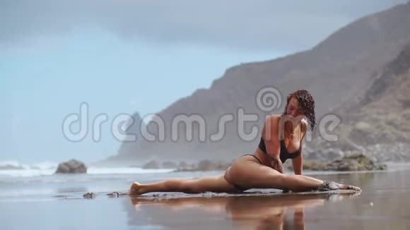 在海边做瑜伽的女孩站在他手上的一座姿势桥上体操伸展和视频的预览图
