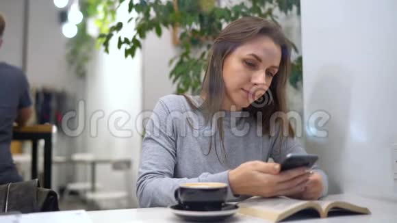 美丽的女人花时间在咖啡馆里使用智能手机和喝咖啡视频的预览图