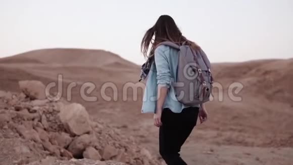 女孩走在山崖边慢动作沙漠峡谷边缘的年轻女性游客大石头和大石头以色列视频的预览图
