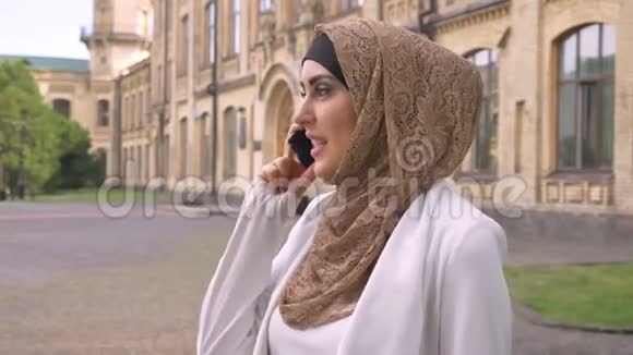 自信的穆斯林商界女性戴着头巾在电话中交谈站在街上背景是建筑女性在视频的预览图