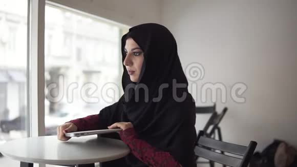 漂亮的女人戴着头巾从桌子上拿出现代笔记本电脑然后走开了慢镜头视频的预览图