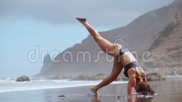 在海边做瑜伽的女孩站在他手上的一座姿势桥上体操伸展和视频的预览图