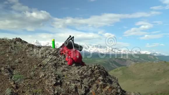 旅行者的红色背包躺在岩石上用于追踪的棍子有一个热水瓶视频的预览图