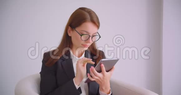 用平板电脑拍摄白种人年轻女商人戴眼镜的特写肖像并用绿色屏幕拍摄视频的预览图