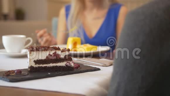 女人面前的一块甜蛋糕在咖啡馆里试着吃甜点视频的预览图