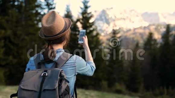 年轻的女旅行者在山上背景下用手机拍照少年拍一张视频的预览图