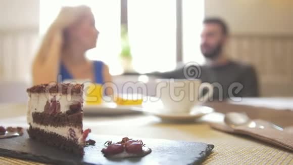 一对夫妇在咖啡馆喝咖啡时盘子里的甜切片蛋糕视频的预览图