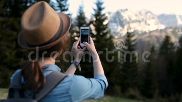 有魅力的女孩旅行者在山上的背景下用手机拍照为游客拍照视频的预览图