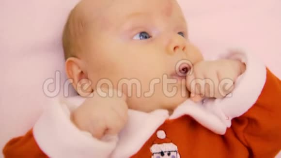 可爱的小宝宝穿着红色连衣裙躺在床上视频的预览图
