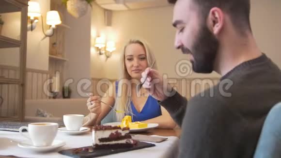 年轻人和女人在咖啡馆里品尝他们的甜点视频的预览图