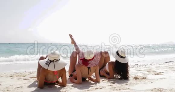 三个女孩躺在沙滩上的后视角享受阳光女性游客在暑假视频的预览图