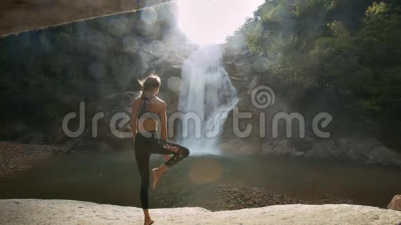 女孩站在瑜伽位置对抗河流太阳射线视频的预览图